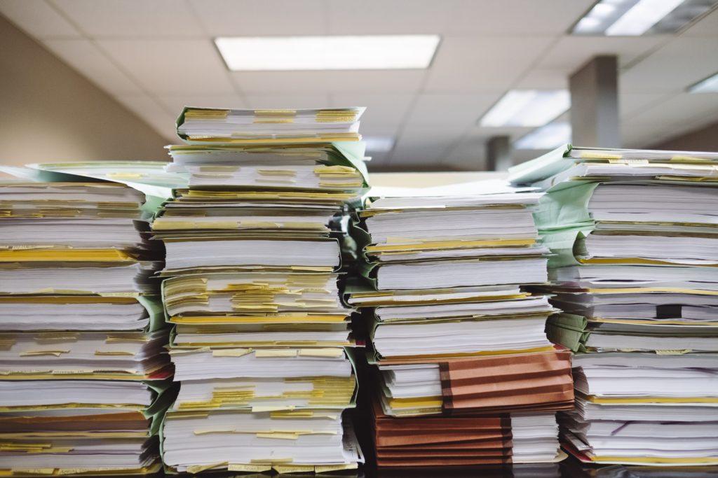 multiple stacks of documents and folders sit together in an office